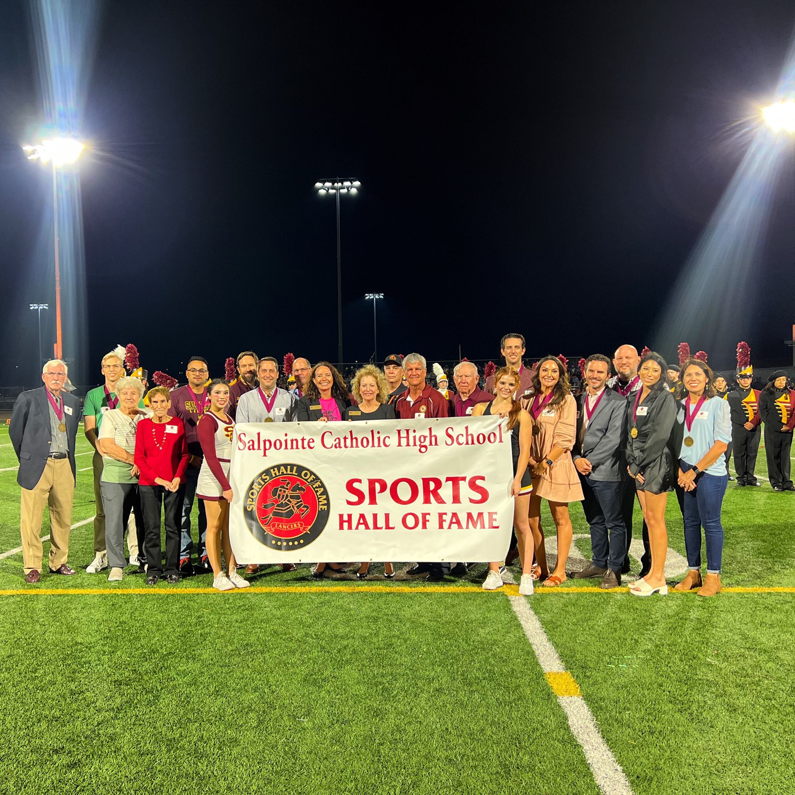 Sports hall of fame members holding banner